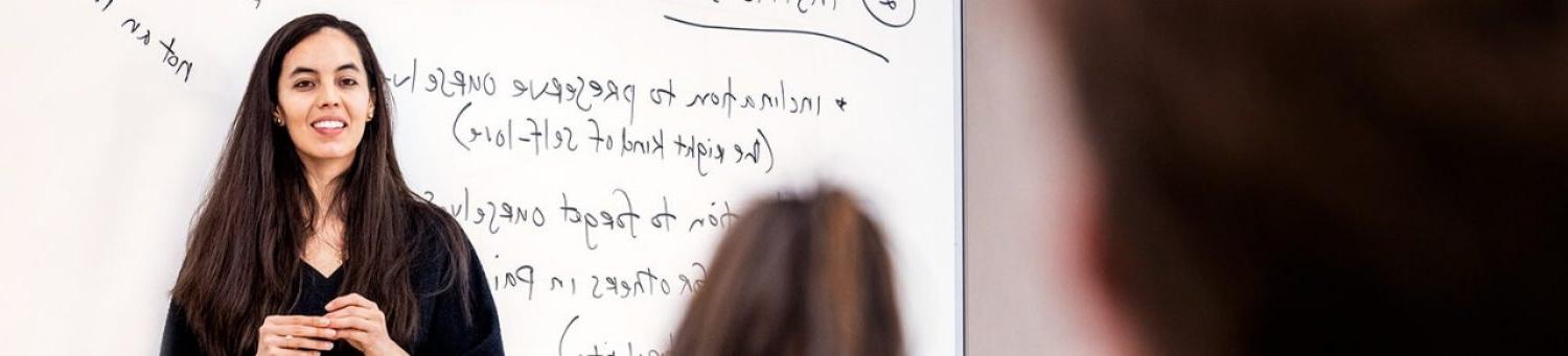 A professor standing in front of a white board